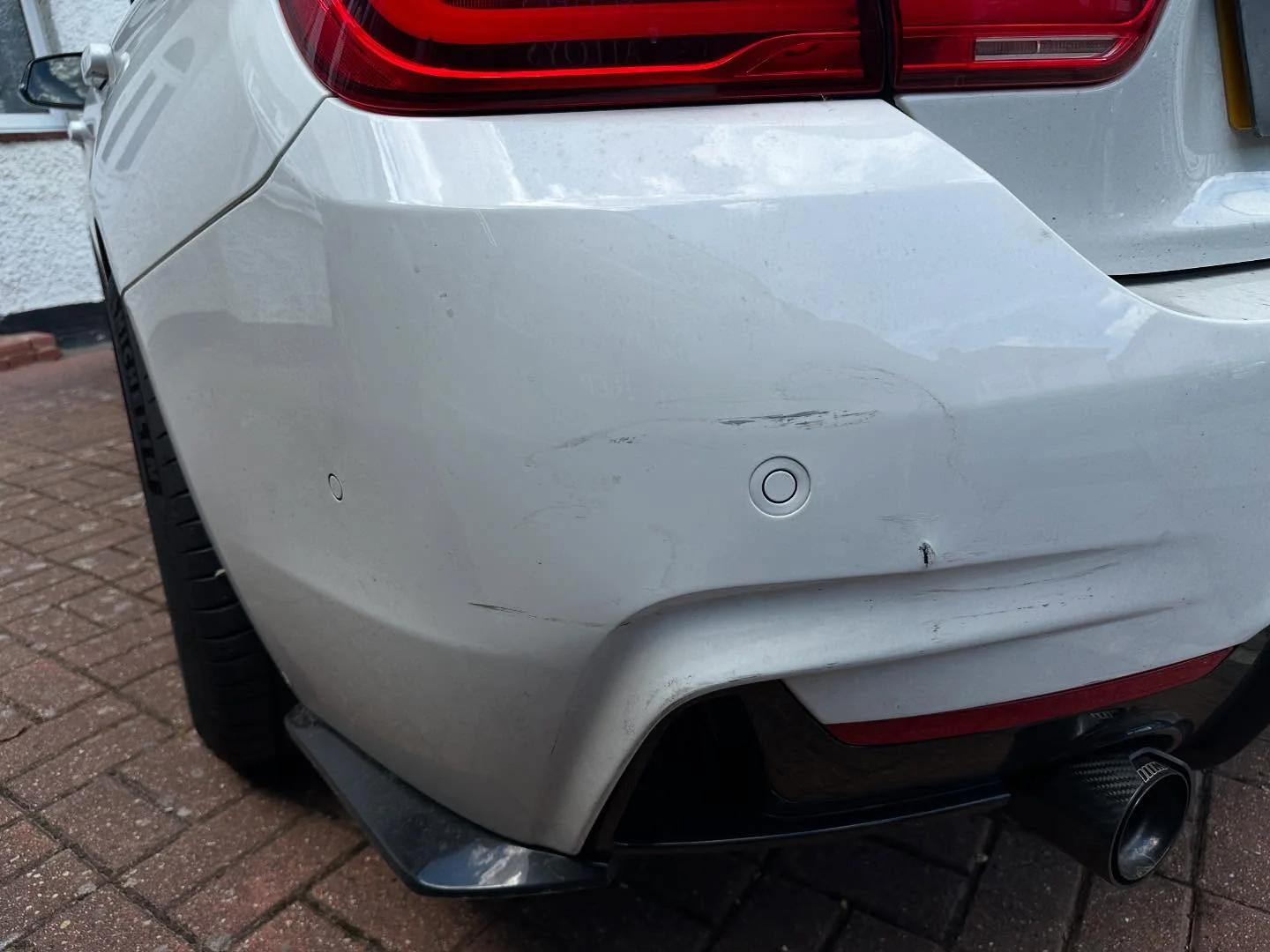 The matching white BMW bumper before repair with visible scratches
